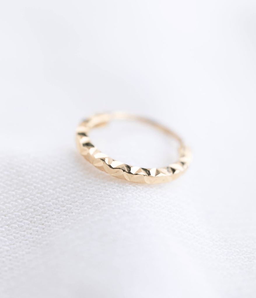 A close-up image of a 14k gold ring with a textured surface, displaying the ring's golden color and delicate details against a white background.